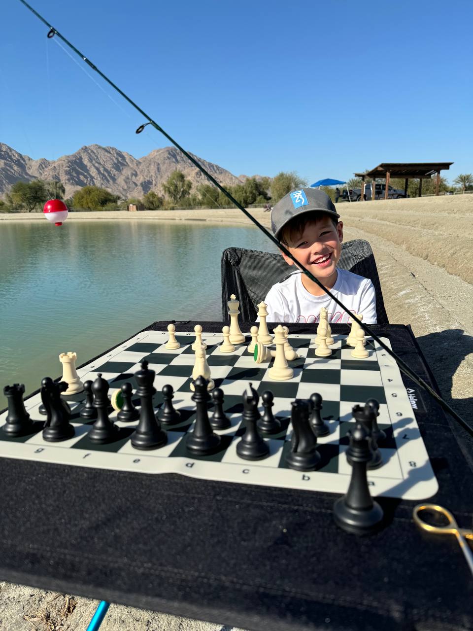 Keith playing chess while fishing at a lake.